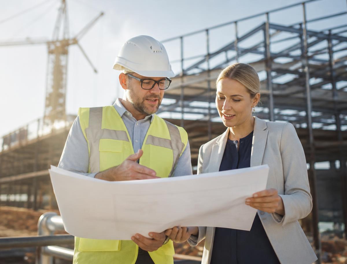 A site manager and an architect reviewing drawings together on a modern construction site
